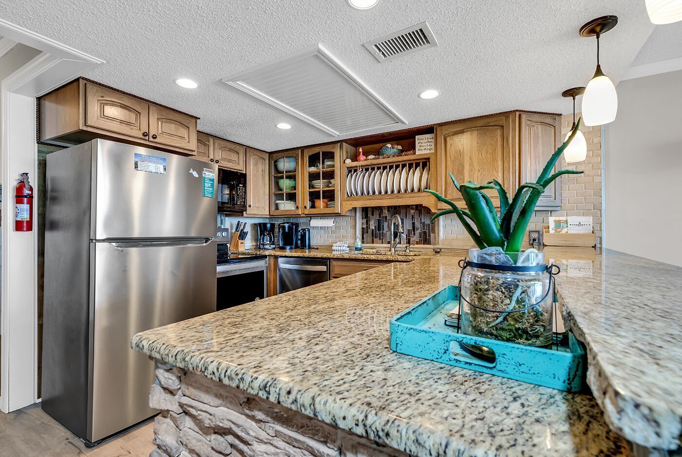 A modern kitchen with granite countertops, stainless steel appliances, wooden cabinets, and a central island.