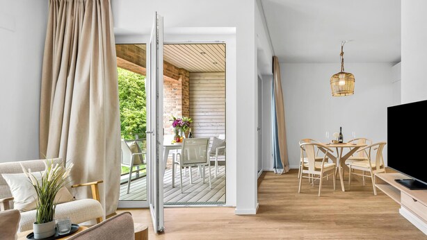 Un salon moderne doté d’une porte-fenêtre coulissante donnant sur une terrasse extérieure.