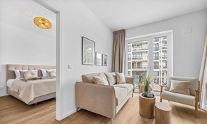 A modern living room with a sofa, armchair, and a round wooden coffee table. - Hafenliebe: Your Seaside Retreat with Balcony & Sea Views (Lübeck)