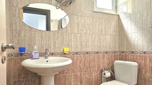 Ein Badezimmer mit Waschbecken, Spiegel, Toilette und gefliesten Wänden.