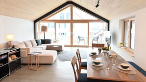 Un salon moderne avec un canapé, une table basse et une table à manger pour quatre personnes.