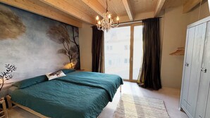 Une chambre à coucher avec un lit, un lustre, une armoire et une vue par la fenêtre.