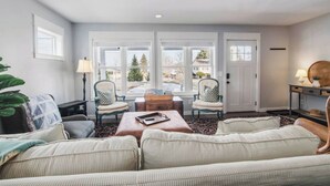 A living room with a large window, a sofa set, a coffee table, and two armchairs. - High Tide: Harbor View: Walk2town/Beach: sleeps 12 (Boyne City)