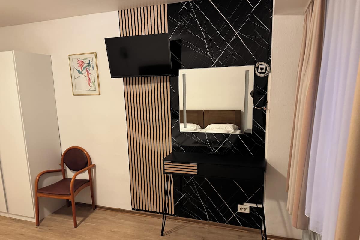 A modern room with a black and white tiled wall, a wooden chair, a small desk, and a bed.