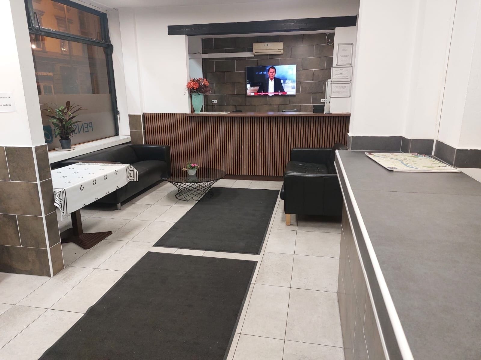A reception area with a TV, seating, and a counter.