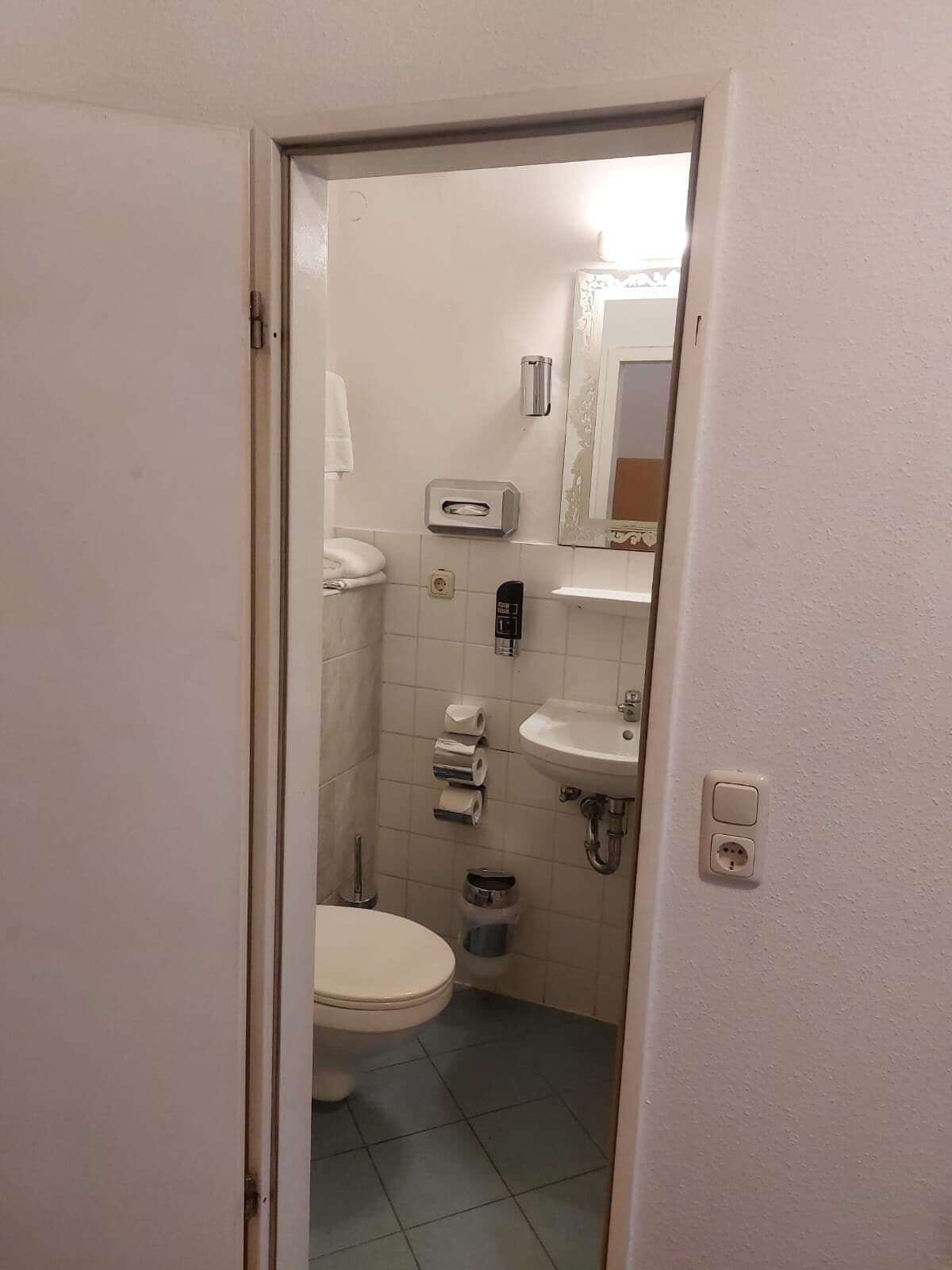 Ein kleines, sauberes Badezimmer mit Toilette, Waschbecken und Spiegel.
