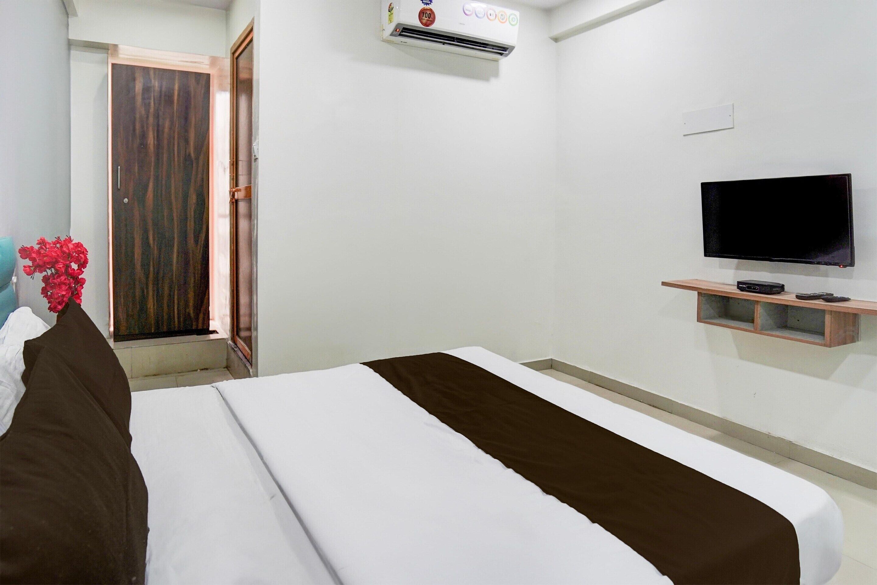 Ein Hotelzimmer mit einem Bett, einem Fernseher, einer Klimaanlage und einem Holzregal.