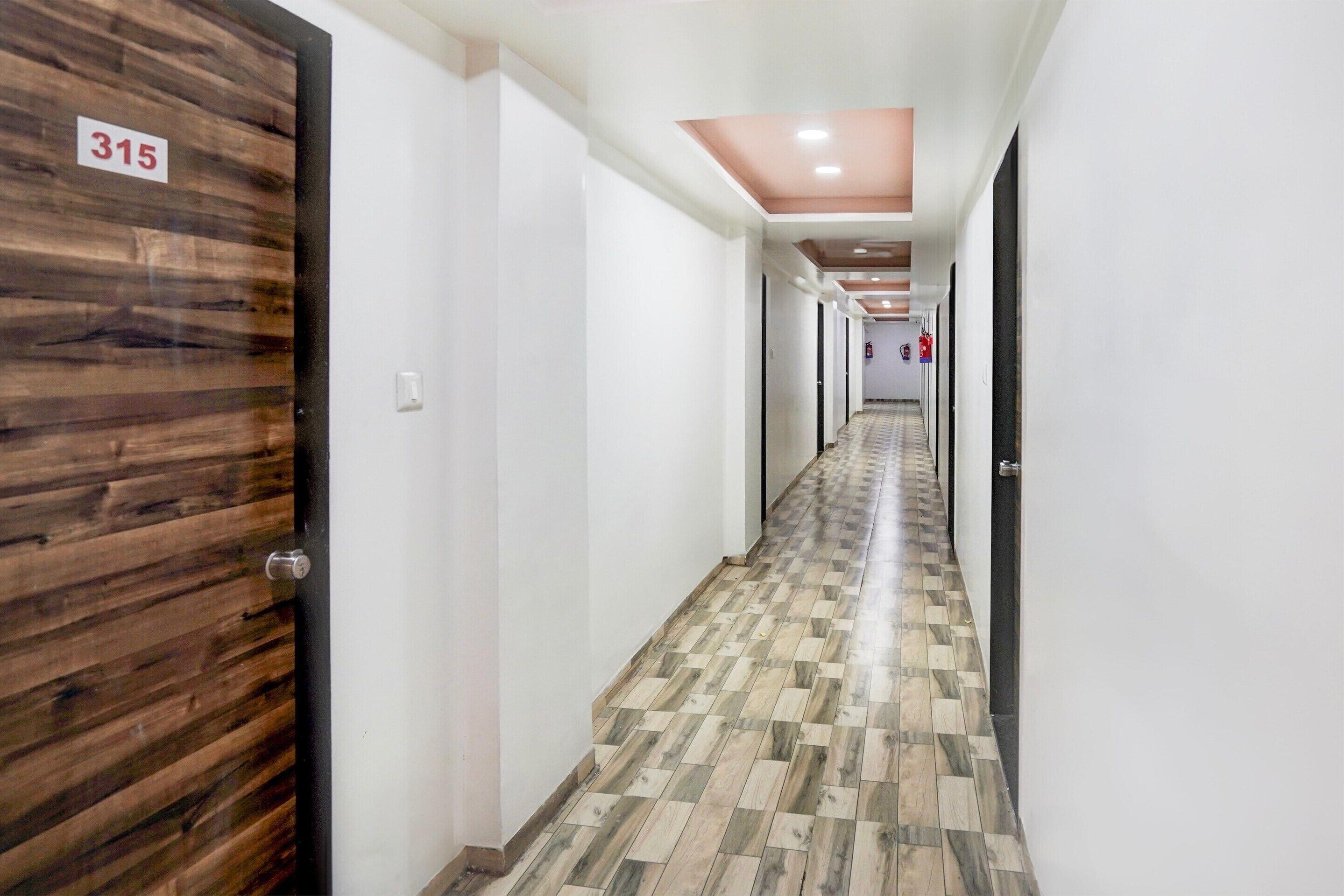 Un couloir d’hôtel avec des portes en bois, numérotées 315, et un sol à motifs.