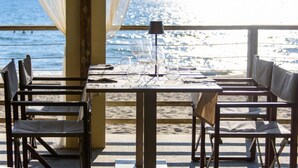 A table set for dining with chairs, a lamp, and a view of the ocean. - Riva degli Etruschi triple room (San Vincenzo)