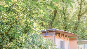 A small, single-story building with a sloped roof, surrounded by dense foliage. - Riva degli Etruschi triple room (San Vincenzo)