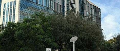 A modern building with large glass windows and a flat roof, surrounded by trees and a clear sky.