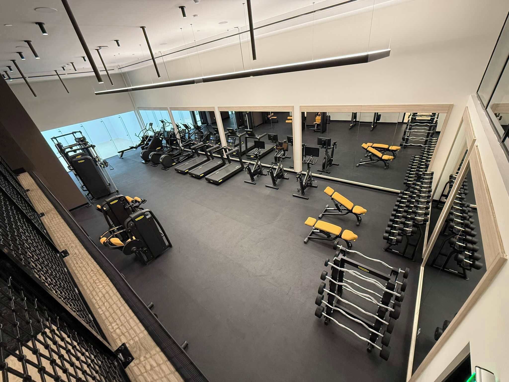 A gym with various exercise equipment, including treadmills, weight machines, and dumbbells.