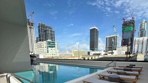 A rooftop pool with lounge chairs and a city view. - Downtown Miami 1BR Walk to Bayside Kaseya Gym Pool (Miami)