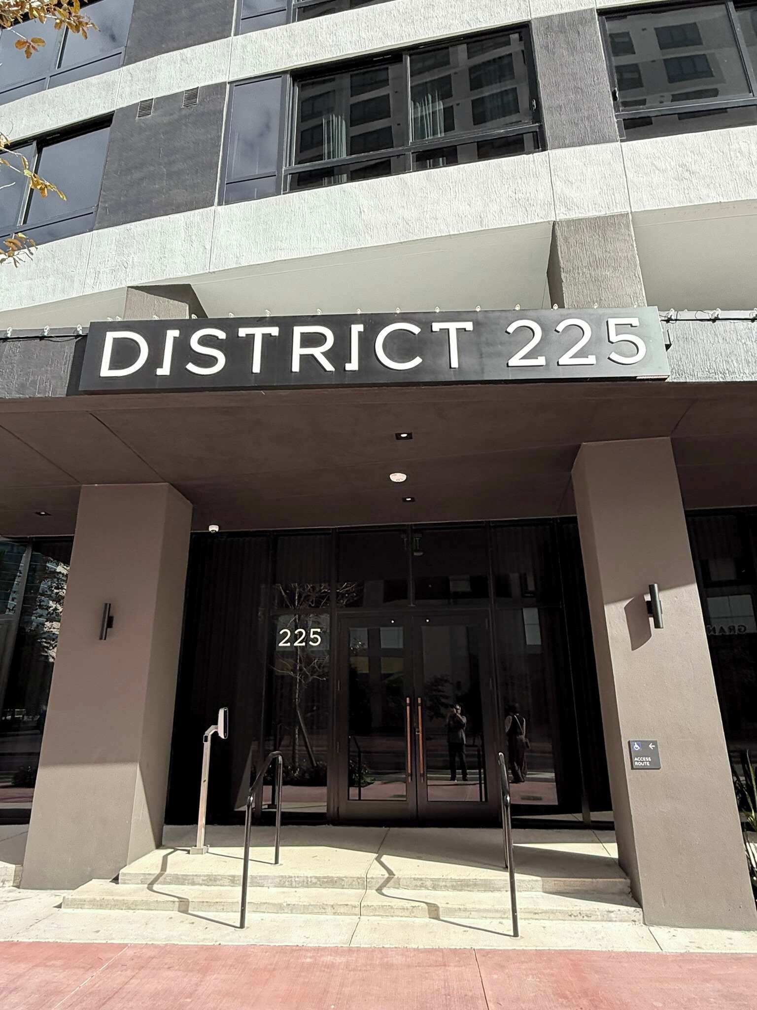 The entrance to District 225 with a clear sign, a glass door, and a set of stairs leading up to the entrance.