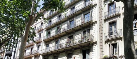 A multi-story building with balconies, a sign for "OPTICA GRAN VIA," and a "P" parking sign.