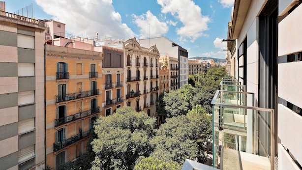 A multi-story urban building with balconies and a glass railing. - Enjoy Apartments Maria (Barcelona)