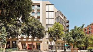 A modern building with multiple floors, large windows, and a mix of balconies and terraces. - Enjoy Apartments Maria (Barcelona)