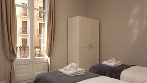 A hotel room with two beds, a wardrobe, and a window with curtains. - Enjoy Apartments Sofia (Barcelona)