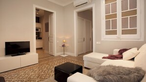 A living room with a flat-screen TV, a white sofa, a black coffee table, and a patterned carpet. - Enjoy Apartments Sofia (Barcelona)