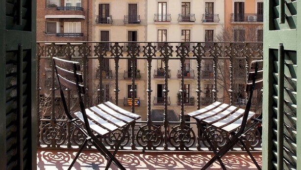 A balcony with wrought iron railings and two lounge chairs. - Enjoy Apartments Sofia (Barcelona)