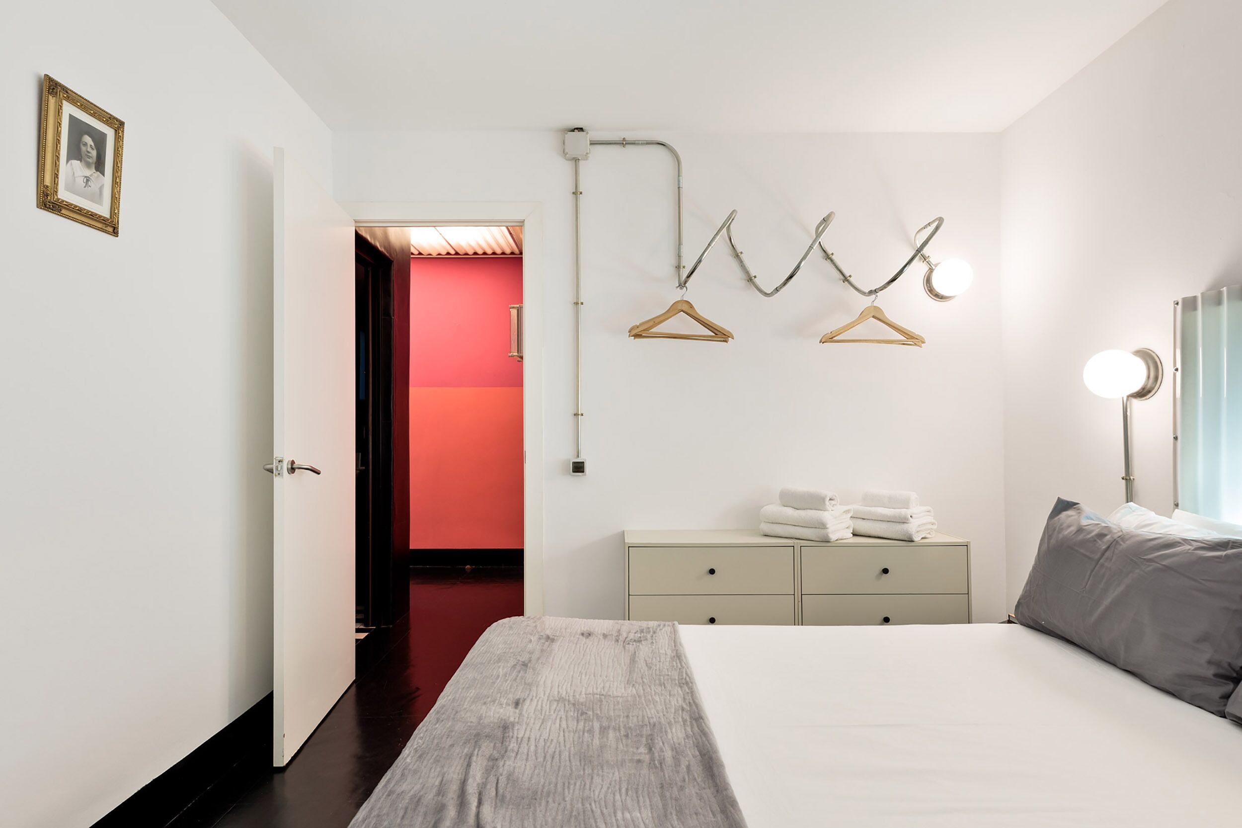 Ein Hotelzimmer mit Bett, Nachttisch mit Handtüchern, Schrank und beleuchtetem Spiegel.