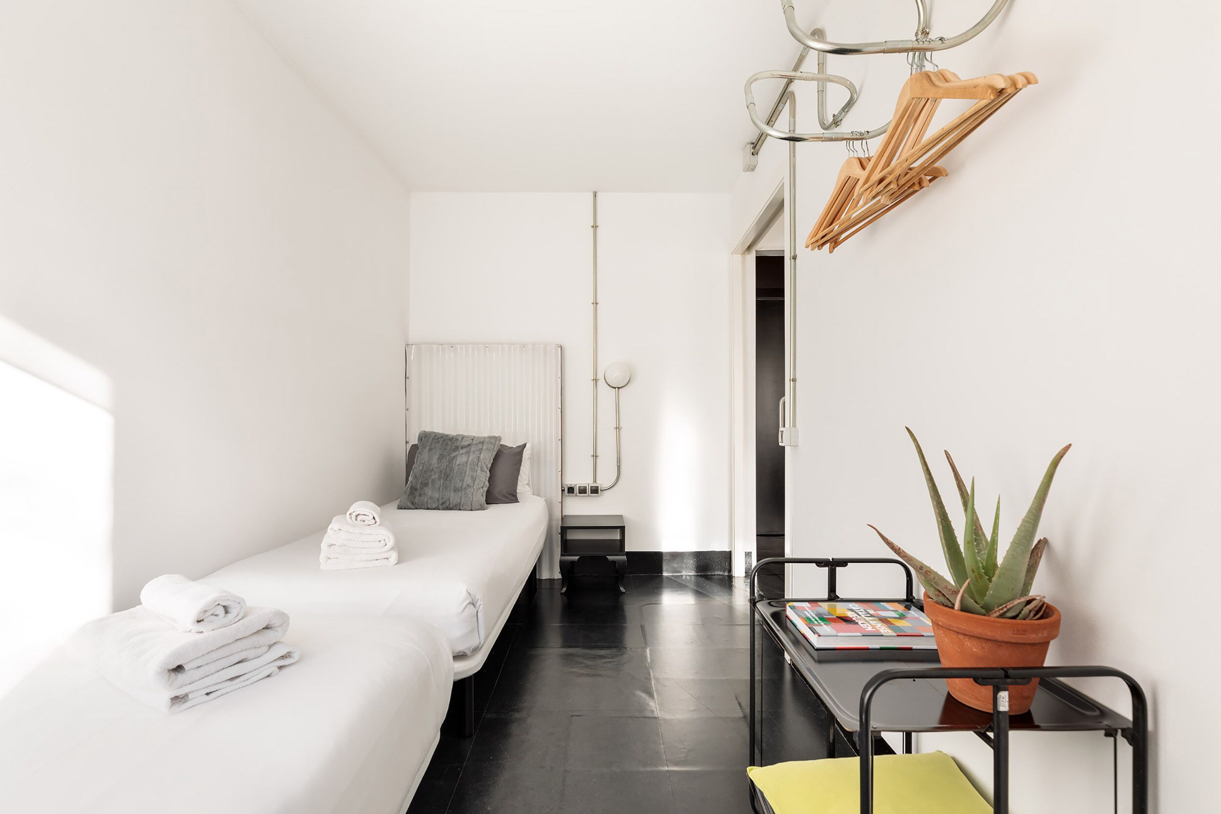 Une petite chambre moderne, avec un lit, une petite table ornée d’une plante et une chaise.
