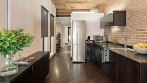 A modern kitchen with a brick wall, stainless steel appliances, and a dark wood floor. - Enjoy Apartments Urban Retreat Valencia (Barcelona)