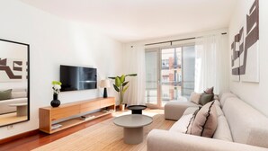 Ett modernt vardagsrum med en soffa, ett soffbord, en tv och en växt.