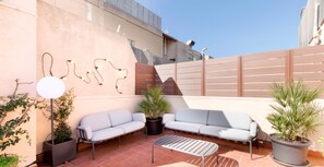A patio with two white sofas, a metal table, and potted plants. - Enjoy Apartments Calle Paris Super Stylish (Barcelona)