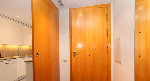 A modern kitchen with white cabinets, a stainless steel sink, and a wooden door. - Enjoy Apartments Calle Paris Super Stylish (Barcelona)