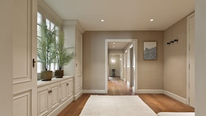 Un pasillo con piso de madera, muebles de cocina blancos y una alfombra blanca.