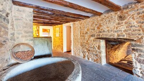 A rustic stone interior with exposed wooden beams, a stone fireplace, and a stone bench. - Casa Fumanal - Unique Property for up to 24 (Abizanda)