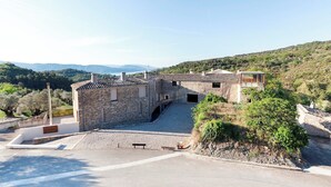 A stone building with a sloped roof, a small balcony, and a paved area in front. - Casa Fumanal - Unique Property for up to 24 (Abizanda)
