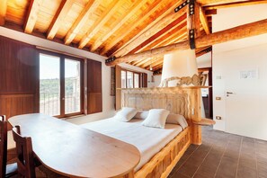 A bedroom with a wooden headboard, a bed with pillows, a wooden table, and a large window. - Casa Fumanal - Unique Property for up to 24 (Abizanda)