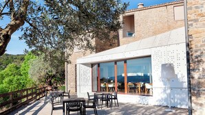 A modern building with large glass windows, outdoor seating, and a stone facade. - Casa Fumanal - Unique Property for up to 24 (Abizanda)