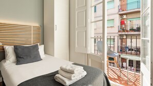Une chambre d’hôtel avec un lit, une fenêtre donnant sur un balcon et une porte.