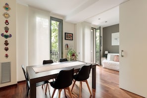 A modern dining area with a long table, black chairs, and a view through large windows. - Frida by EnjoyApartments (Barcelona)