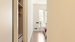 Un corridoio stretto con pavimento in legno che conduce a una camera da letto con un letto e una finestra.
