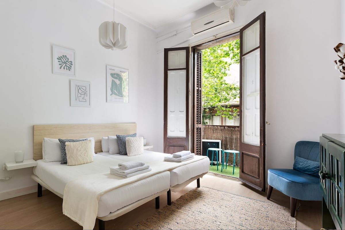 A bedroom with a bed, bedside tables, a chair, and a view of the outdoors.