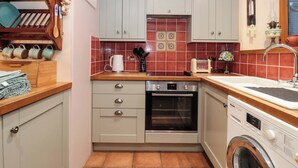 Una cucina compatta con forno a incasso, lavatrice e lavandino.
