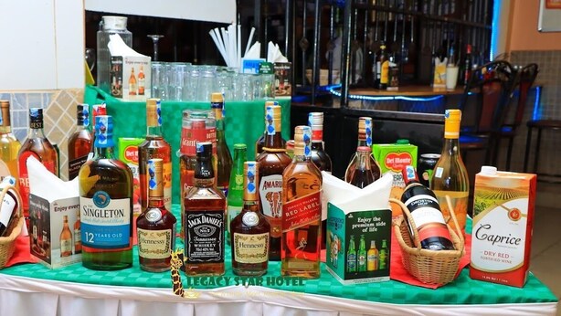 A variety of liquor bottles and boxes on a table at a hotel bar. - Legacy Star Hotel Chuka (Chuka)