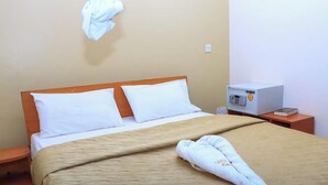 A hotel room with a bed, a wooden headboard, a bedside table with a radio, and a towel on the bed. - Legacy Star Hotel Chuka (Chuka)