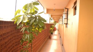 A corridor with a brick wall on one side and a yellow wall on the other, with potted plants along the corridor. - Legacy Star Hotel Chuka (Chuka)