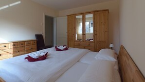Une chambre avec deux lits, une armoire en bois et un miroir.