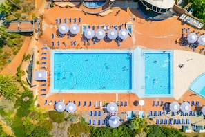 Una piscina al aire libre de temporada, sombrillas, tumbonas