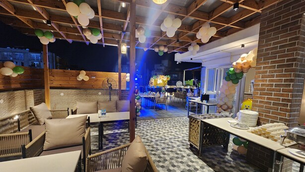 Un espacio comedor al aire libre con mobiliario de mimbre y suelo de baldosas.
