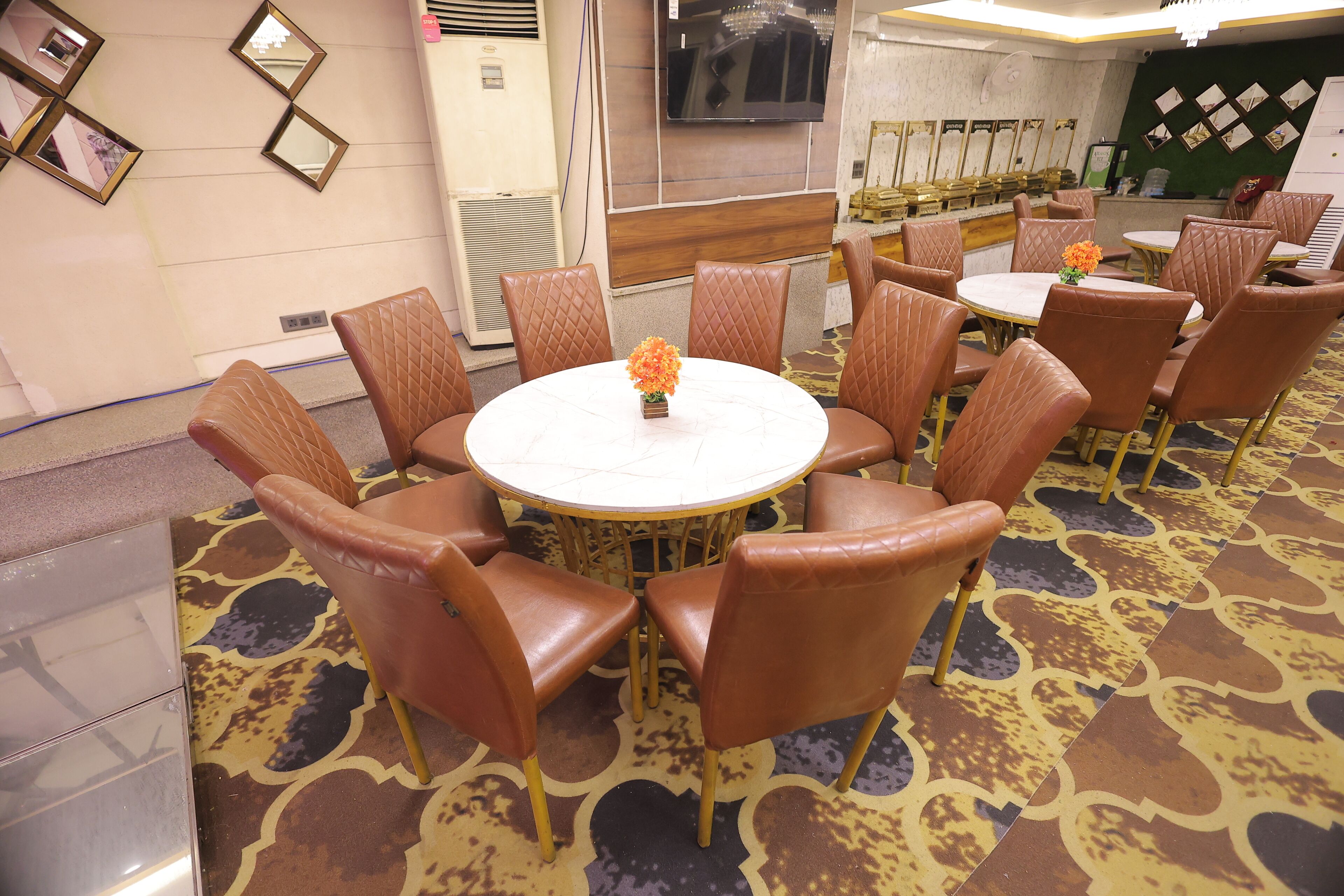 A conference room with a round table, brown leather chairs, and a floral centerpiece.