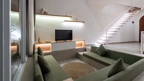 En moderne stue med en grøn sofa, et fladskærms-tv og en trappe.