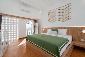 A hotel room with a wooden headboard, a green bedspread, a decorative wall hanging, and a white crib. - Villa Casa Zaya A (Canggu)