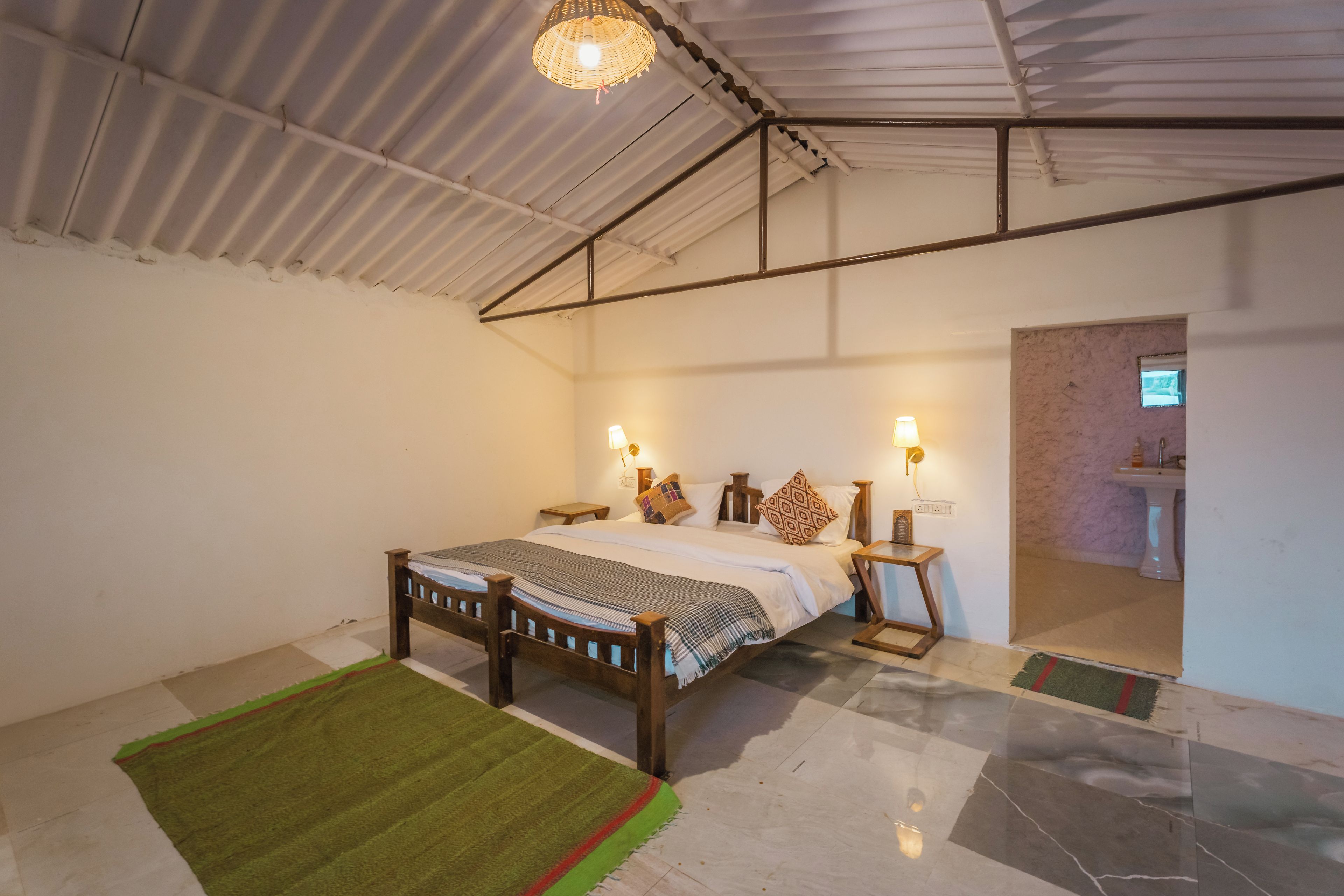 A bedroom with a large bed, bedside lamps, a green rug, and a ceiling fan.